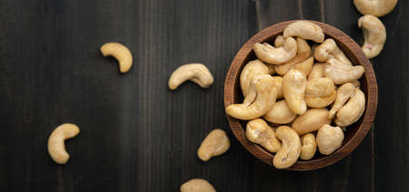 Raw cashew nuts in wooden bowl on rustic tableの写真素材