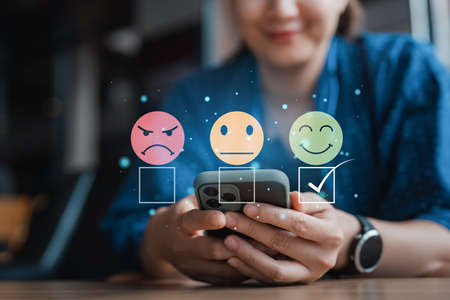 smart woman use smartphone choosing green happy smile face icon. feedback rating and positive customer review experience, satisfaction survey. mental health assessment. world mental health day conceptの写真素材