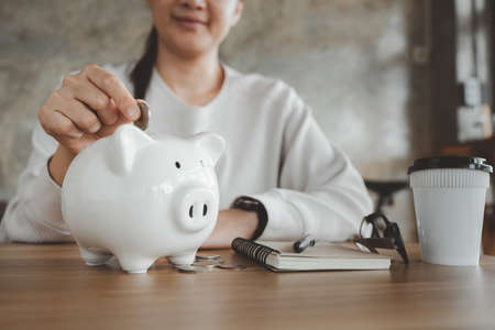 Happy smart asian woman saving money in a piggybank. saving and money concept.の写真素材