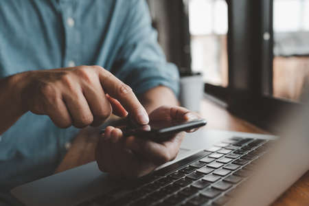 casual Businessman hand holding and using smartphone for sms messages, man typing touchscreen cell phone in the office. business, lifestyle, technology and Social media network conceptの写真素材