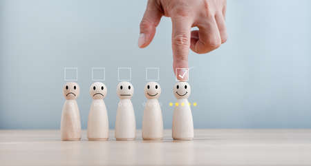 best excellent business services rating customer experience. Satisfaction survey concept. Hand of a businessman chooses a smiley face on wood doll. 5 Star Satisfaction.の写真素材