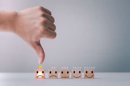 Customer service satisfaction survey concept. Business people or customers are thumbs down to show their satisfaction in service. human hand give a 1 star and unhappy face icon satisfaction rating.の写真素材