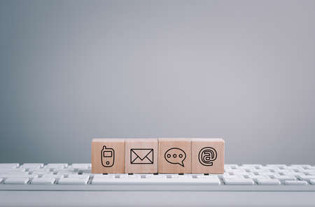 Website page contact us or e-mail marketing concept, Customer support hotline Contact us people connection. cube wood with the email, call phone, address, Chat message icons. on keyboard computer,の写真素材