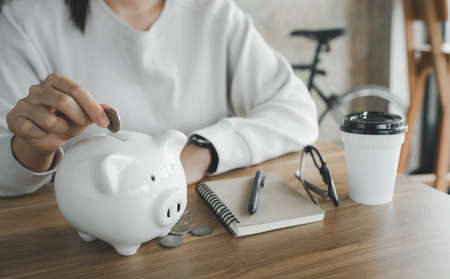 smart Asian female hand putting money coin into piggy for saving money wealth and financial concept.の写真素材