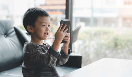 baby cute boy playing games on a tablet or smartphone and watching cartoons.の写真素材