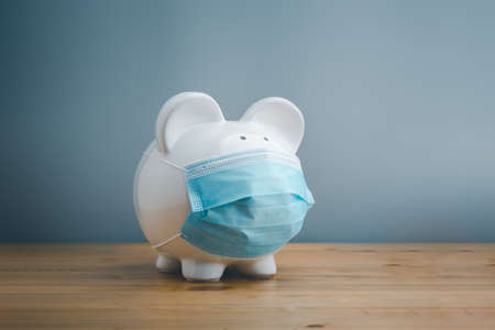 Piggy bank wearing surgical face mask. Global economy during coronavirus pandemic.  Financial crisis, banking concept. saving and investment.の写真素材