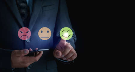 business man use smartphone choosing green happy smile face icon. feedback rating and positive customer review experience, satisfaction survey.の写真素材