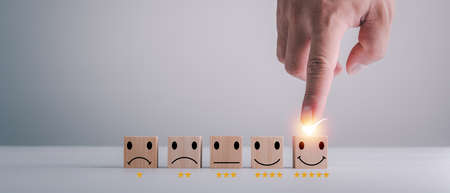 customer services best excellent business rating experience. Satisfaction survey concept. Hand of a businessman chooses a smiley face on wood block cube. 5 Star Satisfaction.の写真素材