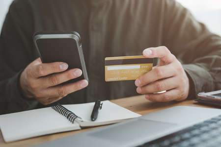 male hands holding a credit card and use mobile phone for Online payment online shoppingの写真素材