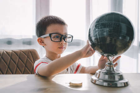 portrait of little funny Asian boy ,toy model earth. the globe, map. Concept travel, education.の写真素材