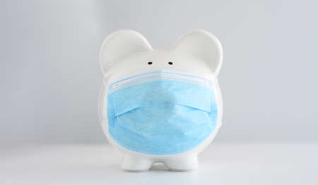Piggy bank wearing surgical face mask. Global economy during pandemic.  Financial crisis, banking...