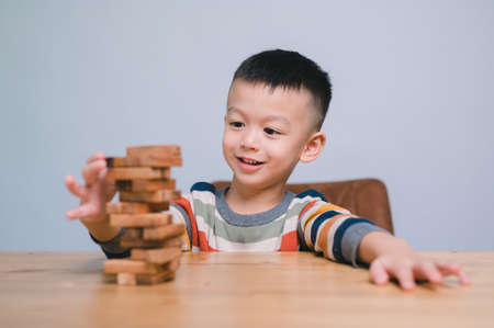 Cheerful Asian boy playing with wooden building blocks . Having fun and learning creativity. smart kid concept.の写真素材