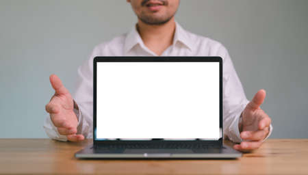 Cropped view Happy Asian man pointing showing with blank white screen of laptop computer. copy space. mock up computer screen.の写真素材