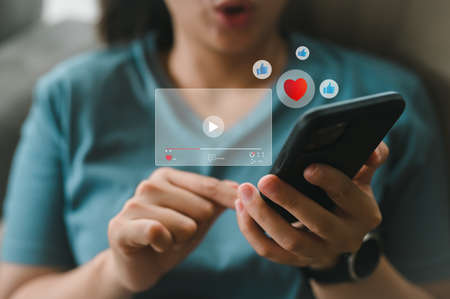 Young woman using smart phone watching live streaming Interesting and popular content, Social media concept.の写真素材