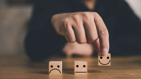 Customer service and Satisfaction concept ,Business people show a feedback with smile face wood cube happy smile face icon to give satisfaction in service. rating very impressed.の写真素材
