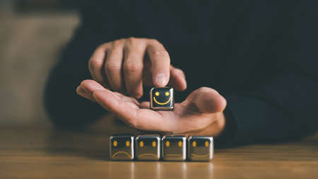 customer services best excellent business rating experience. Satisfaction survey concept. Hand of a businessman chooses a very smile face on wood block cube.の写真素材