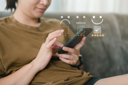 Customer service evaluation concept. smart women use smartphone choosing face smile emoticon....