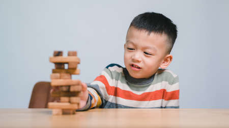 Cheerful Asian boy playing with wooden building blocks. Having fun and learning creativity. smart kid concept. 5years old.の写真素材