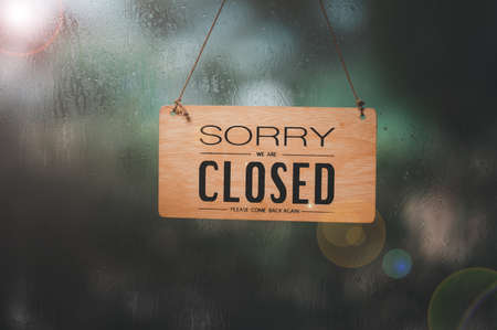 Closed sign in a shop showroom with reflections in rainy day. sign showing the word " SORRY WE ARE Closed ", Closing announcement concept Or stop the business, close the shop.の写真素材