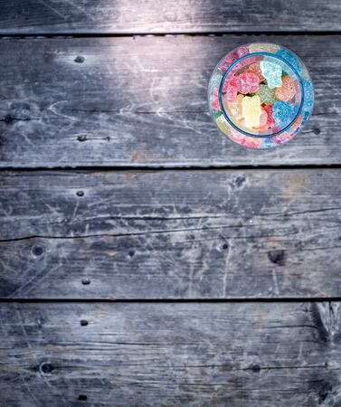 Colourful sour candies in the jar on the wooden floorの写真素材
