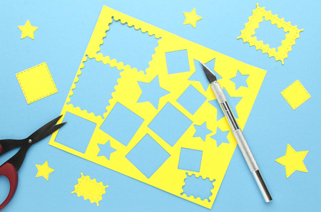 Scalpel, scissors, yellow flat paper shapes on blue backgroundの写真素材