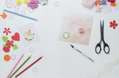 Paper flowers, colored pencils, scissors scattered on the table. The view from the topの写真素材