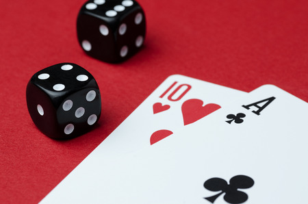 Two cards and black dice on a red background. close up