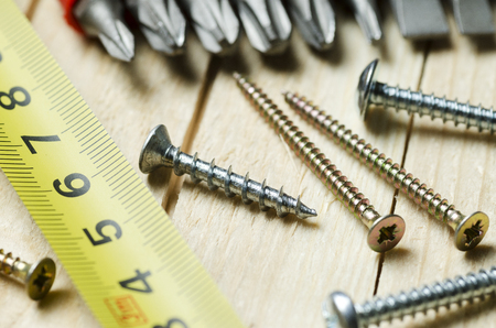 screws and measuring tape on wooden boards, closeup