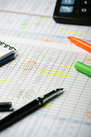 Financial calculations in a table on paper, pen, highlighter and calculator. Verticallyの写真素材