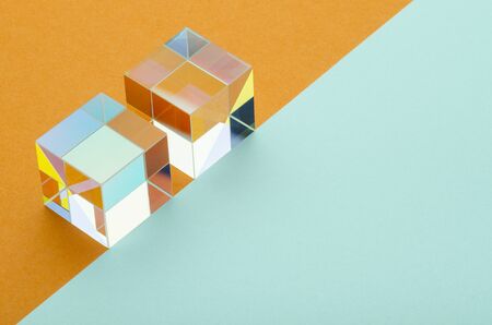 two iridescent glass cubes on an orange and blue backgroundの写真素材