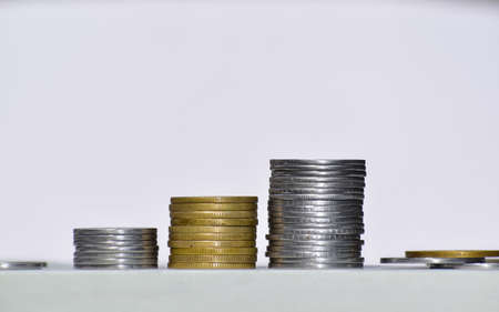 Stacks of silver and golden coins set in a growing direction, isolated on white background. Concept of Saving money, economy, investment, growing business and wealth.の写真素材