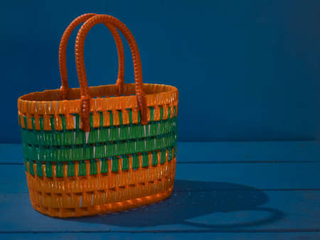 Beautiful women's tote bag on wooden table with isolated blue background. This is a craft plastic wire bag. Multi purpose.の写真素材