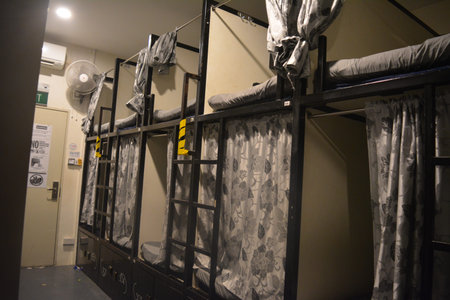 Room with bunk beds separated by plywood partitions and covered with curtains, creating simple...