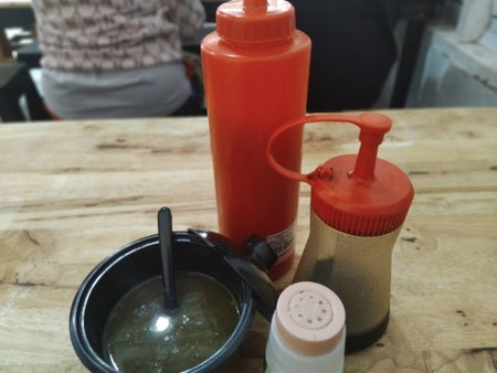 Close-up seasoning condiments arranged on a bakso stall table ready for customers