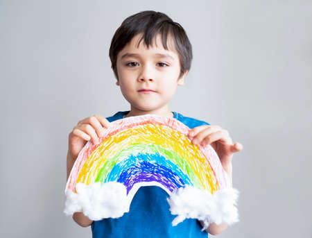 Ortrait  Kid inself isolation holding drawing picture of rainbow on white pape. Child Stay at home...