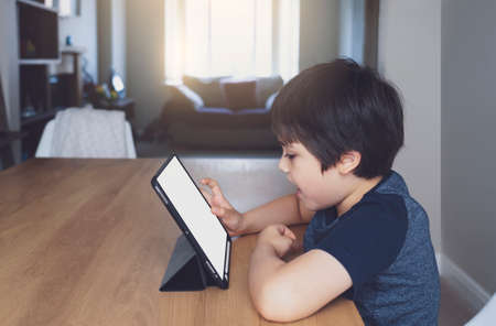 Kid using tablet  studying homework, Child using digital tablet for his online lesson at home during...