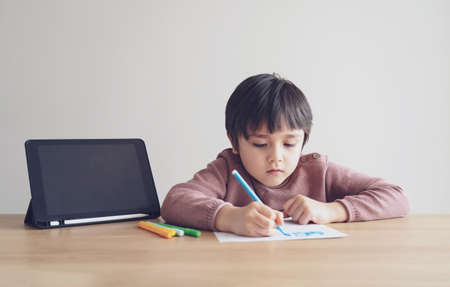 Kid self isolation using tablet for his homework,Child doing using digital tablet searching information on internet during covid 19 lock down,Home schooling,Social Distance,E-learning online educationの写真素材