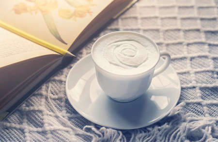 Home made cup of latte coffee beans and summer book on coffee table in work space with morning light or Cozy scene of relaxing in afternoon break , tea time with coffee in living roomの写真素材