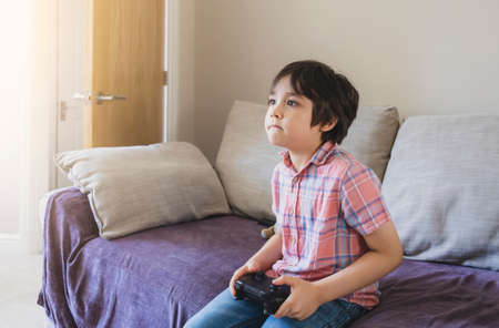 Portrait of kid holding video game or game console.Child playing game online at home while school...
