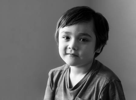 Black and white portrait of healthy kid, Happy child looking at camera with smiling face, Candid shot cute little boy relaxing stay at home during covid lock down.Positive children conceptの写真素材