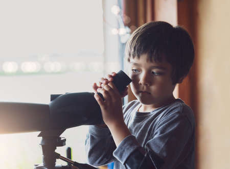 High key protrait of Kid boy looking through monocular, Active kid explorer bird watching in the animals station view point,  Child explorer with wildlife nature in summer campの写真素材