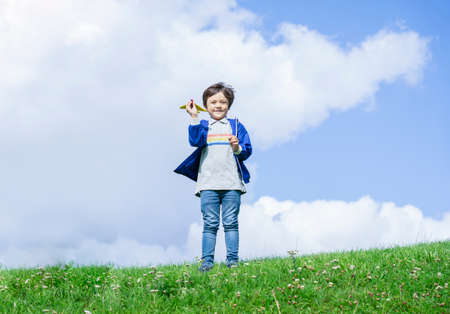 Portrait active little boy playing with toy airplane against green nature background, Child throwing foam airplane, Kid playing in the park,  Childhood outdoor activity concept.の写真素材