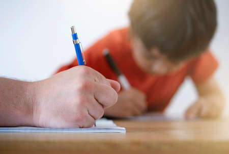 Cropped shot father helping his boy with homework, Dad and Son doing homework together, Teacher teaching little boy how to write. Man hand holding pencil, Education conceptの写真素材