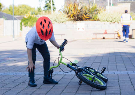 High key portrait of young boy try to picking up his his bike up from the floor,  School kid learns to ride a bike.の写真素材