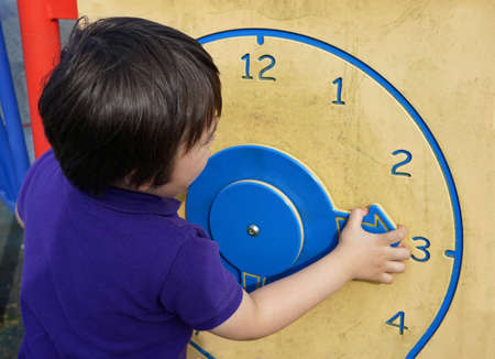 Child learning time with wooden clock at  play ground in summer, Kid boy learning to tell time, kid hands, Concept of learning by playing for children developmentの写真素材