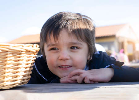 Hight key protait of happy kid boy with smiling face sitting with easter basket hunting on the...