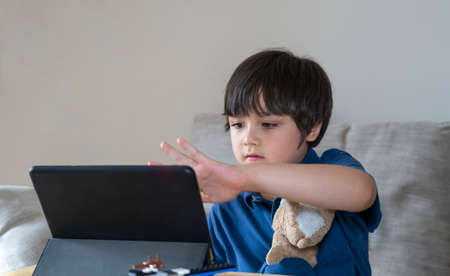 School Kid using tablet for his homework, Child looking at digital tablet with thinking face, Young...
