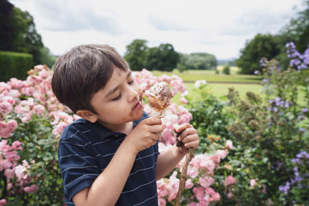 Portrait happy boy eating ice cream, Child boy having fun playing in the garden in sunny day summer, Candid shot Young boy with dirty face from ice creamの写真素材