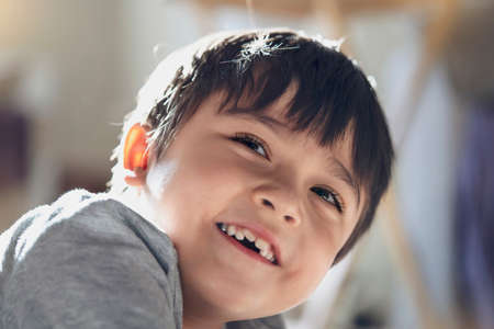 Candid shot happy kid looking up with smiling face, High key light healthy child relaxing at home, Positive Little boy having fun on his own with blurry sunny light background.の写真素材