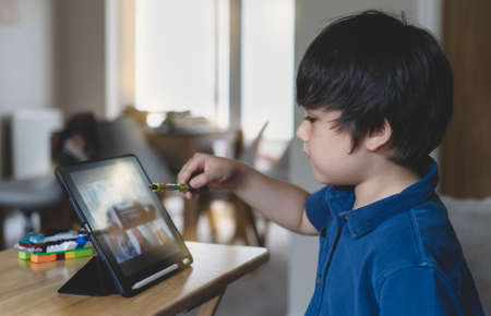 School Kid using tablet  taking with his class friends, Child showing his plastic toys to his...